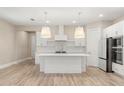 Modern white kitchen with island, stainless steel appliances, and light wood floors at 15424 Enchanted Melody Way, Winter Garden, FL 34787