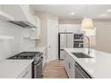 Modern white kitchen with island, stainless steel appliances, and light wood floors at 15424 Enchanted Melody Way, Winter Garden, FL 34787