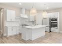Modern white kitchen with island, stainless steel appliances, and light wood floors at 15424 Enchanted Melody Way, Winter Garden, FL 34787