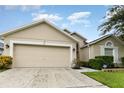 Tan one-story house with a two-car garage and landscaped front yard at 170 Thornbury Dr, Kissimmee, FL 34744