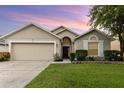 Tan one story house with two car garage and manicured lawn at dusk at 170 Thornbury Dr, Kissimmee, FL 34744
