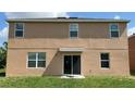 Two-story house with tan siding, multiple windows, and a sliding glass door leading to a backyard at 108 Country Walk Cir, Davenport, FL 33837