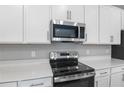 Stainless steel range and microwave above white cabinets at 4255 Sawtooth Ct, Tavares, FL 32778