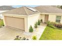 House exterior view with tan siding, two-car garage, and neatly landscaped pathway at 47 Willow Ln, Kissimmee, FL 34759