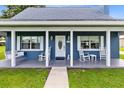 Front view of a charming blue house with a white porch and rocking chairs at 435 Lantern Dr, Kenansville, FL 34739