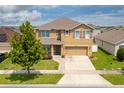 Two-story house with a tan exterior, brown roof, and a two-car garage at 1885 Hickory Blf, Kissimmee, FL 34744