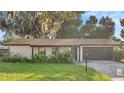 Updated ranch home exterior boasts a newly painted stone facade, dark brown garage door, and lush green lawn at 3722 Paige St, Port Orange, FL 32129