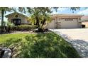 House exterior featuring stone accents, landscaping, and a three-car garage at 203 Escondido Ct, Poinciana, FL 34759