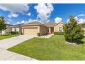 Tan house with a red door, two-car garage, and green lawn at 3663 Julius Estates Blvd, Winter Haven, FL 33881