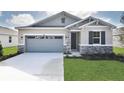 New construction home with gray siding, stone accents, and a two-car garage at 4216 Sawtooth Ct, Tavares, FL 32778