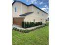 Tan two-story house with brown garage door and landscaped lawn at 1523 Wynford Cir, Tavares, FL 32778
