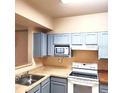 Galley kitchen with light gray cabinets and standard appliances at 3701 Castle Pines Ln # 3914, Orlando, FL 32839