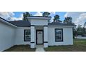 White house with black accents, a gray walkway, and a partially visible yard at 2648 Sw 146 Th Place Rd, Ocala, FL 34473