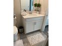 Clean bathroom with white vanity, gray tile floor, and a decorative rug at 1077 Quaker Ridge Ln, Davenport, FL 33896