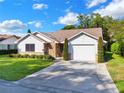 Front view of a single-story house with a white garage door and nicely landscaped lawn at 1016 Monroe Ave, Saint Cloud, FL 34769