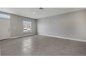 Empty living room with grey walls, tile floors, and a window at 1808 Coriander Dr, Kissimmee, FL 34759