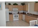 Kitchen with light wood cabinets, white appliances, and tile floor at 608 Copeland Dr, Haines City, FL 33844