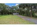 Newly built home nestled amongst mature trees with a gravel driveway at 424 Wilder Rd, Lakeland, FL 33809