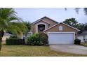 Tan two-story house with a white garage door and landscaping at 1652 Dunes Ct, Haines City, FL 33844