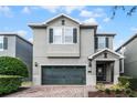 Two-story house with gray siding, dark green garage door, and brick paved driveway at 7617 Brookhurst Ln, Kissimmee, FL 34747