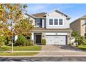 Two-story house with gray siding, stone accents, and a three-car garage, tree in front at 3425 Halsway Dr, Orlando, FL 32824