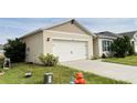 Tan house with white garage door, landscaping, and fire hydrant at 1286 Iguana Loop, Davenport, FL 33897