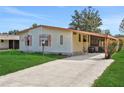 Single-wide mobile home with carport and lush green lawn at 450 Tivoli Park Dr, Davenport, FL 33897