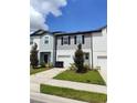 Two-story townhome with gray and light blue siding, two-car garage, and landscaping at 114 Mandovi St, Davenport, FL 33837
