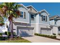 Two-story townhome with light blue siding, two-car garage, and palm tree at 12456 Turtle Grass Dr, Orlando, FL 32824