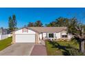 White house with brick accents, a two-car garage, and a landscaped yard at 1402 Westminster Way, Kissimmee, FL 34744