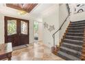 Elegant entryway with double doors, tile flooring, and a staircase with patterned carpet at 7435 Gathering Ct, Reunion, FL 34747