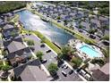 Aerial view showcasing a community with a lake, pool, and numerous houses at 2280 San Vital Dr # 105, Kissimmee, FL 34741