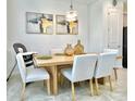 Modern dining room with light wood table and six light-grey cushioned chairs at 742 Longboat Dr, Davenport, FL 33896