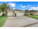 Two-car garage, light beige exterior, and landscaped front yard at 3838 Gulf Shore Cir, Kissimmee, FL 34746