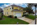 Two story yellow house with a two car garage and palm trees at 8544 Palm Harbor Dr, Kissimmee, FL 34747