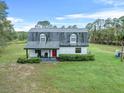 White ranch home with gray roof and red front door, nestled in a spacious yard at 965 Keen Rd, Frostproof, FL 33843