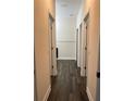 Long hallway with light walls, dark flooring, and doors to bedrooms and bathrooms at 221 Elm Ct, Poinciana, FL 34759