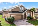 Two-story house with a brown exterior, two-car garage, and palm tree at 131 Cadiz Loop, Davenport, FL 33837