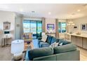 Spacious living room with a teal sectional sofa, large sliding glass doors, and a view of the water at 445 Via Abruzzi St, Poinciana, FL 34759