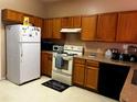 Galley kitchen with wood cabinets, white appliances, and tile floor at 481 Peppermill Cir, Kissimmee, FL 34758