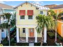 Two-story yellow house with orange accents and a metal roof, surrounded by palm trees at 3075 Key Lime Loop, Kissimmee, FL 34747