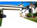 Front view of a light tan house with a white garage door and stone accents at 1569 Thetford Cir, Orlando, FL 32824