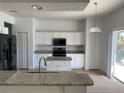 Modern kitchen with white cabinets, granite countertops, and stainless steel appliances at 14716 Yorkshire Run Dr, Orlando, FL 32828