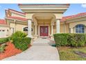 Elegant entryway with red double doors and columns at 2789 Kissimmee Bay Cir, Kissimmee, FL 34744