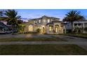 Luxury home exterior at twilight with illuminated landscaping and uplighting at 6018 Tarawood Dr, Orlando, FL 32819