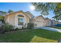 Tan house exterior with a two-car garage and neatly landscaped yard at 7900 Elmstone Cir, Orlando, FL 32822