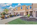 Tan three-story townhouses with brown garages and a paved driveway at 1336 Chelsea Dr, Davenport, FL 33897