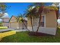 Tan house with a large window, palm trees, and a well-maintained lawn at 3571 Maple Ridge Loop, Kissimmee, FL 34741