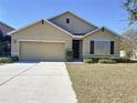 Tan one-story house with a two-car garage and landscaping at 102 Lake Tracy Ct, Haines City, FL 33844