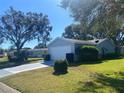 Side view of a light blue vinyl-sided house with a two-car garage, landscaping, and driveway at 5062 El Destino Dr, Leesburg, FL 34748